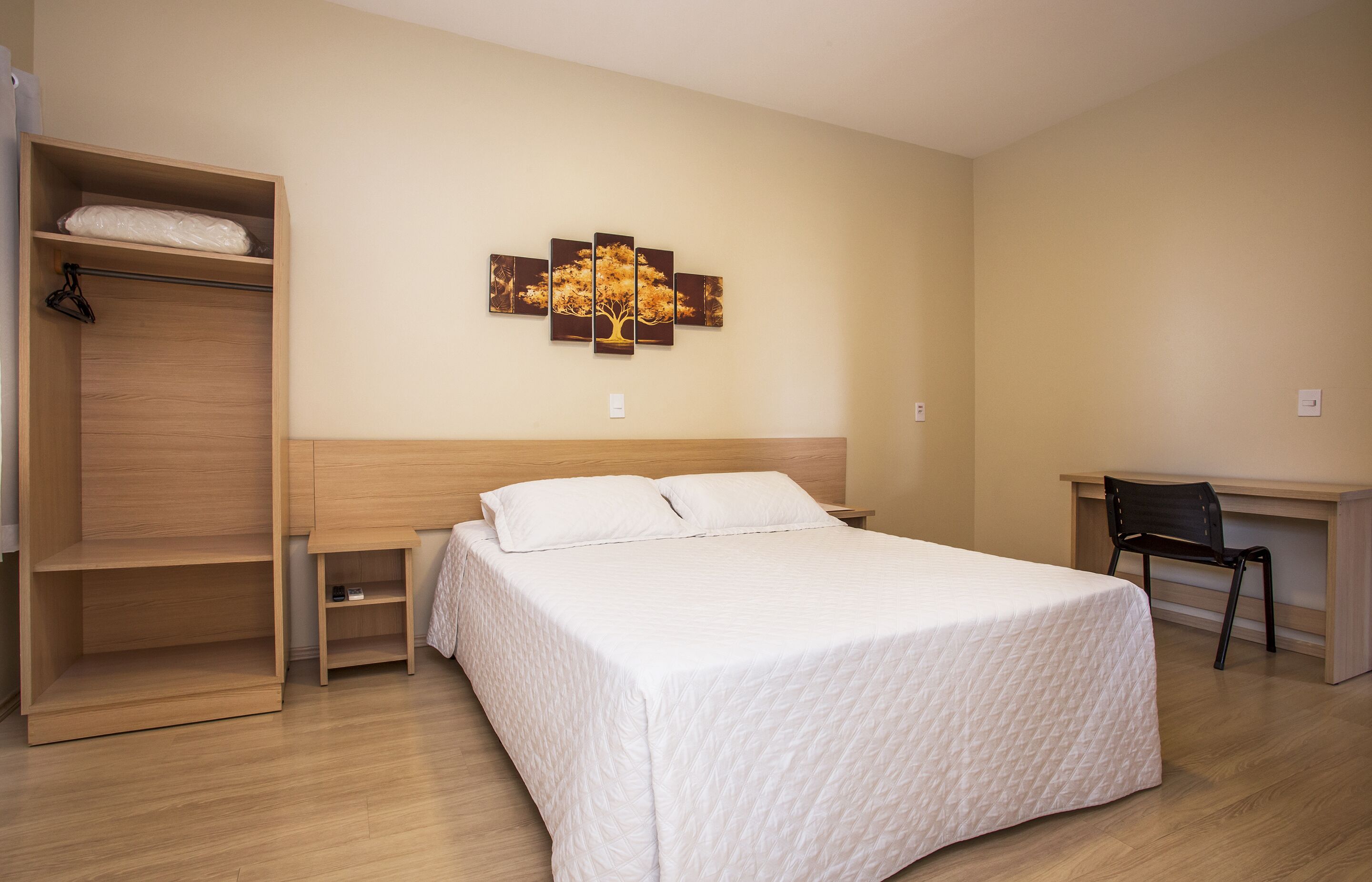 Un dormitorio con una cama, un armario de madera, un escritorio y una silla.