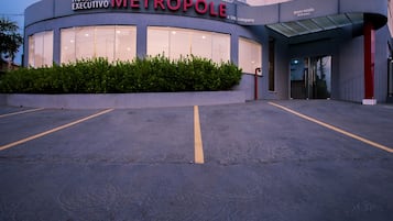 The exterior of the Hotel Metropole, featuring a curved facade, large windows, and a parking lot.