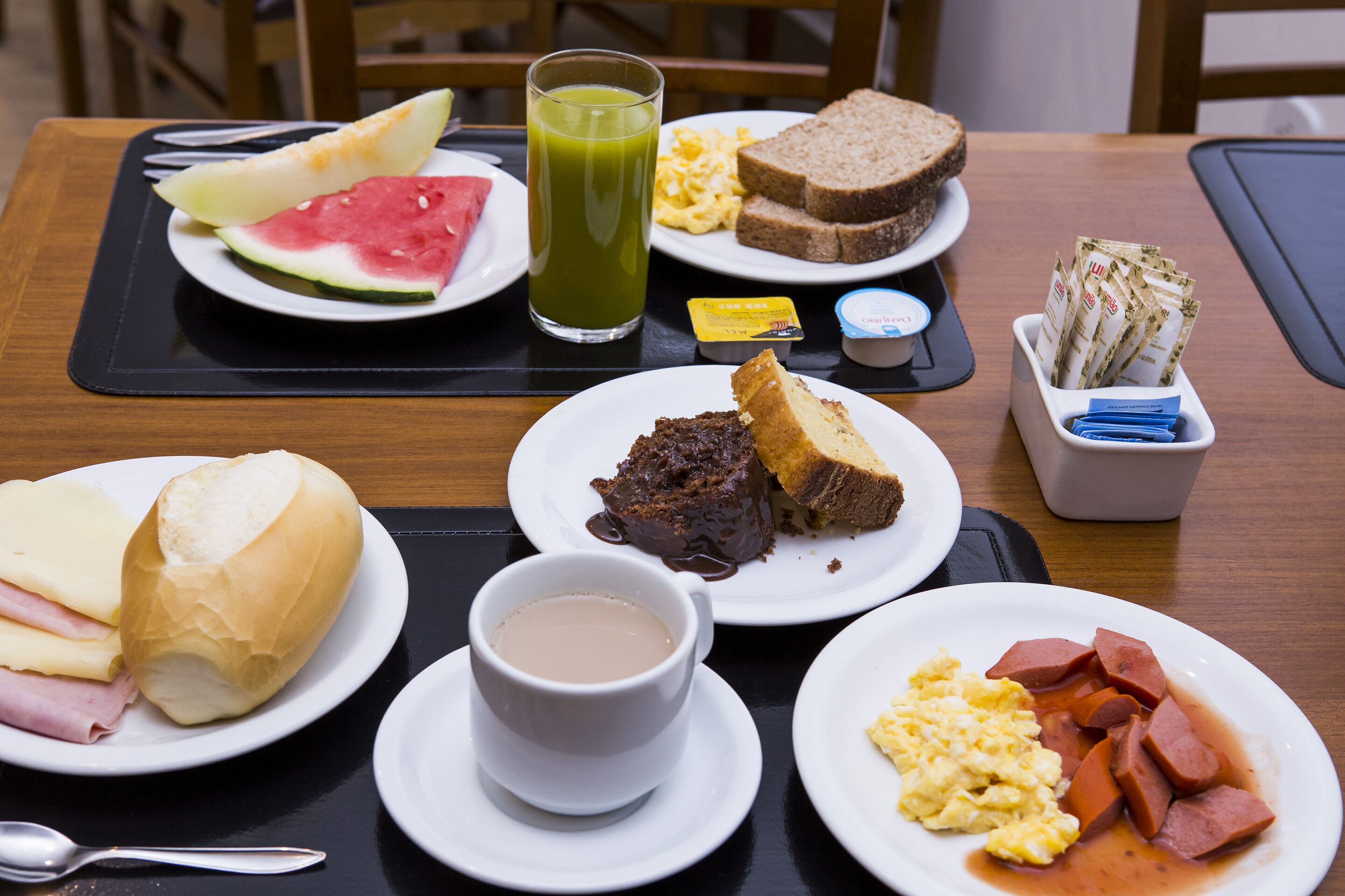 A breakfast table with plates of food, a glass of juice, and a cup of coffee.