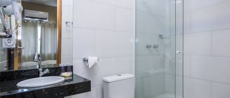 Un baño con ducha de vidrio, un lavamanos con encimera de mármol y un inodoro.