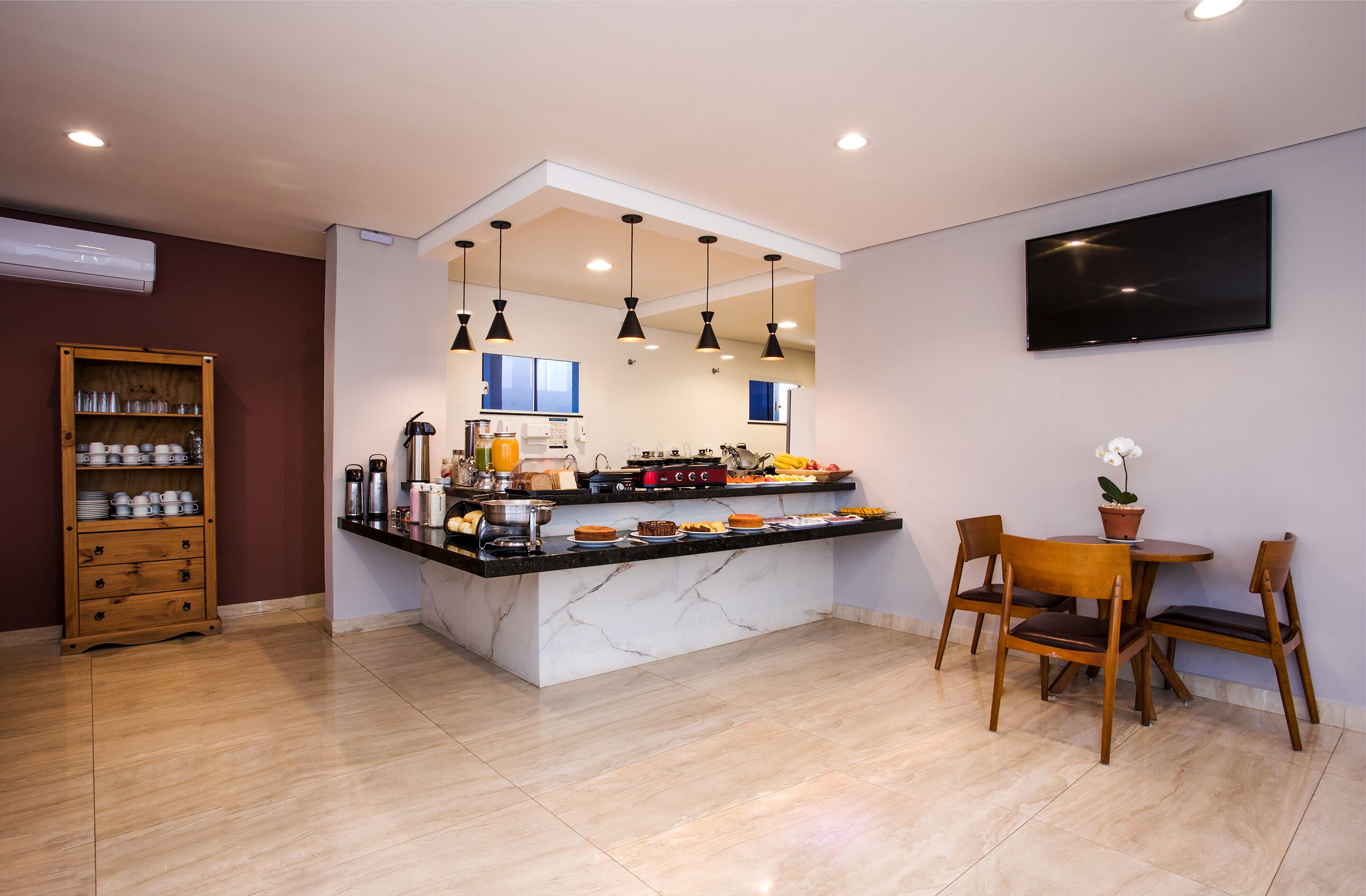A modern kitchen with a marble island, pendant lights, and a dining area with wooden chairs.