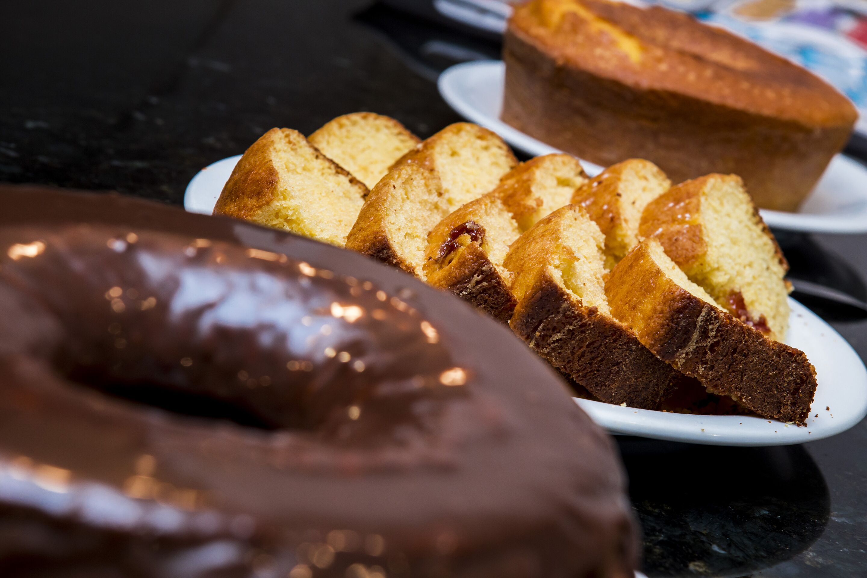 Variedad de productos horneados en platos, incluyendo un donut cubierto de chocolate y rebanadas de pastel.