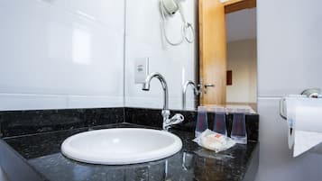 A bathroom with a white sink, black marble countertop, and a hairdryer mounted on the wall.