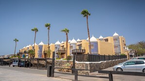A hotel with multiple white-domed buildings, palm trees, and a stone wall.