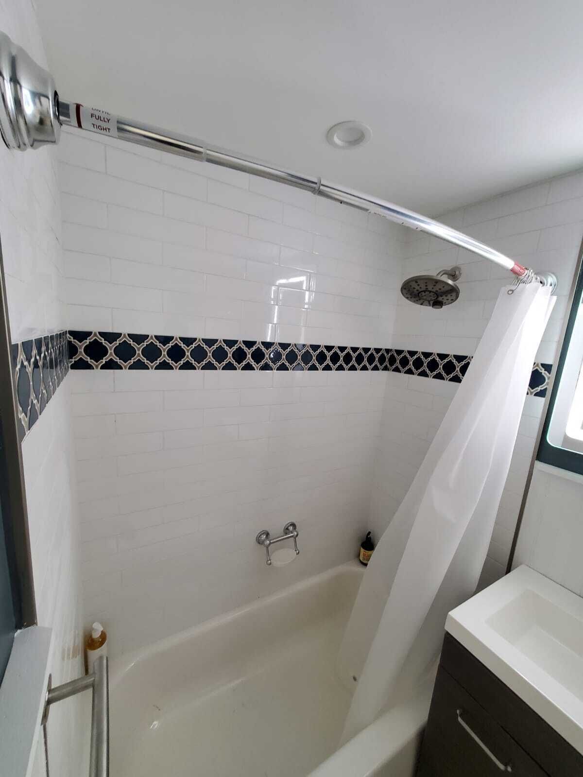 Une salle de bain avec une baignoire blanche, une pomme de douche et un porte-serviettes.