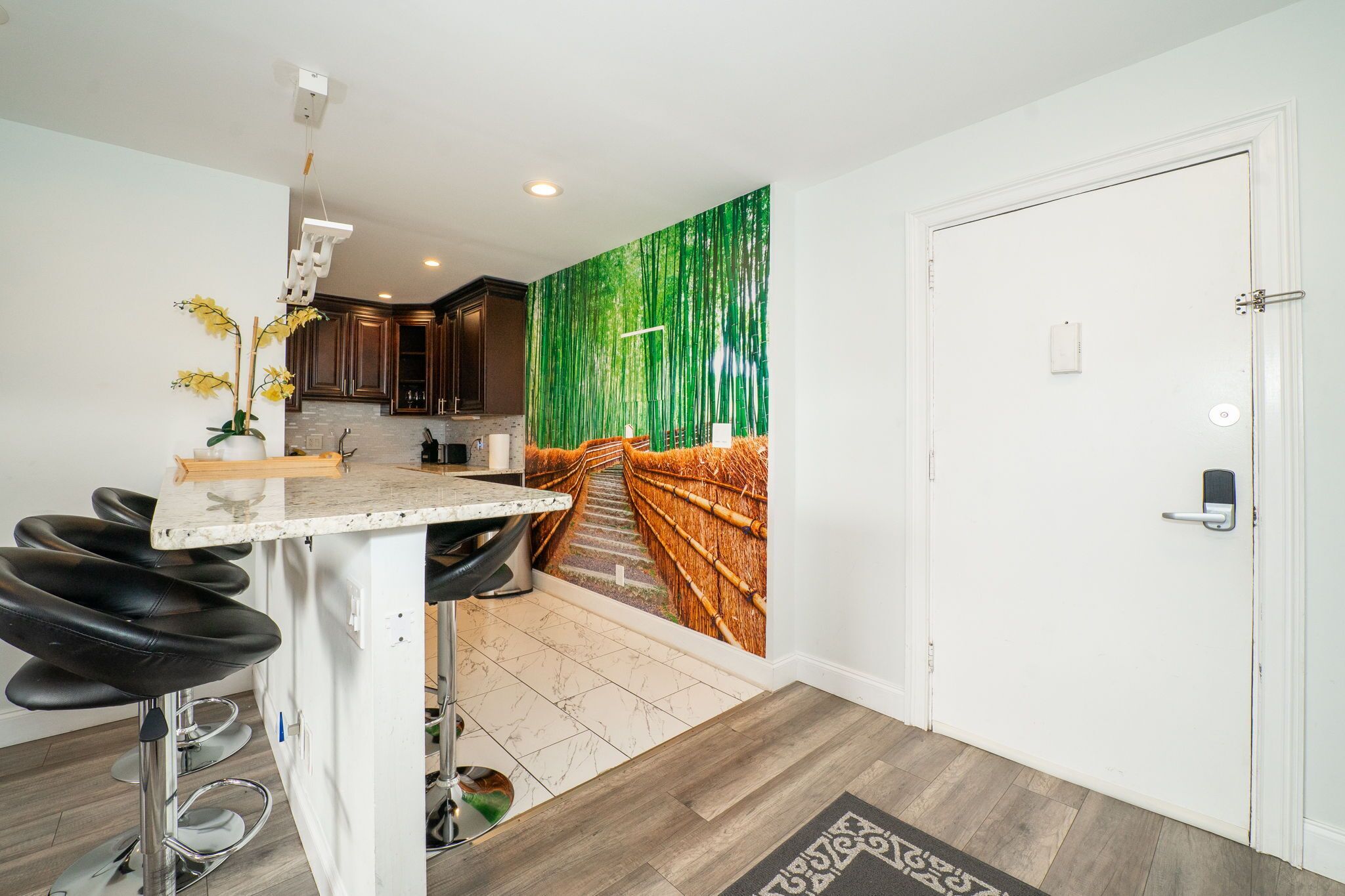 A modern kitchen with a central island, bar stools, and a decorative wall mural.