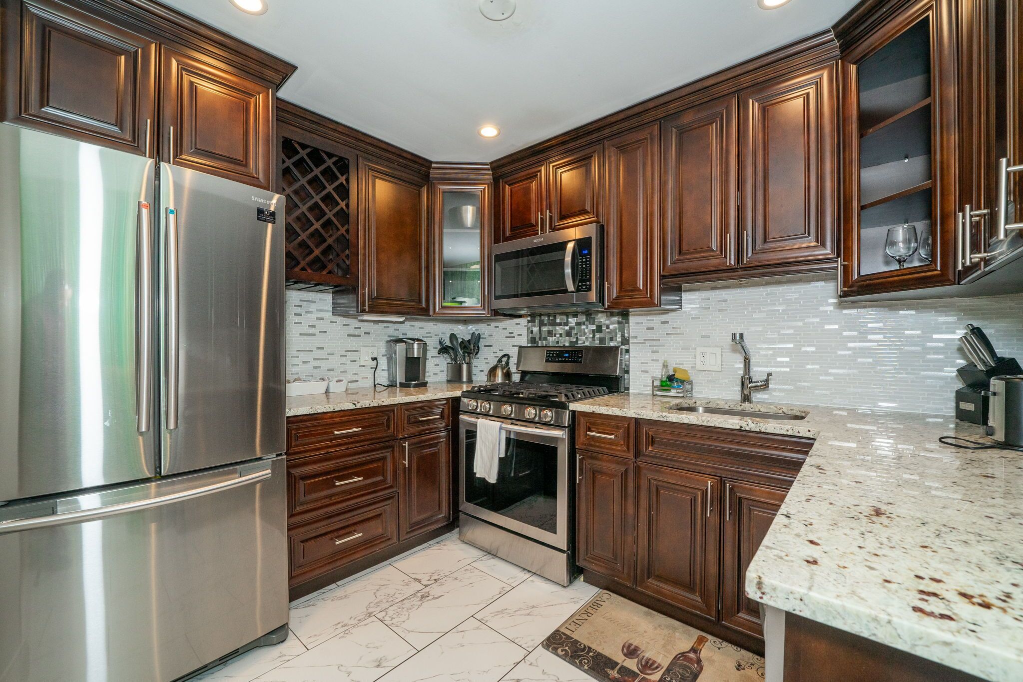 A modern kitchen with stainless steel appliances, wooden cabinets, and a tiled backsplash.