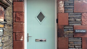 Una porta blu chiaro con una finestra a forma di diamante, una maniglia in metallo e un cartello che riporta la scritta 'The Old Court House'.