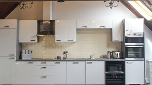 Una cucina moderna con mobili bianchi, una cappa in acciaio inossidabile e un forno integrato.
