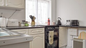 Une cuisine avec des meubles blancs, une cuisinière, une bouilloire et un grille-pain.