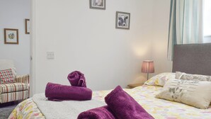 Une chambre d’hôtel avec un lit, une chaise et deux tableaux encadrés au mur.