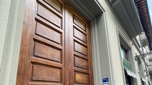 A wooden double door with a brass handle, a small sign above the door, and a window to the right. - Guest house Biffi Simone (Florence)