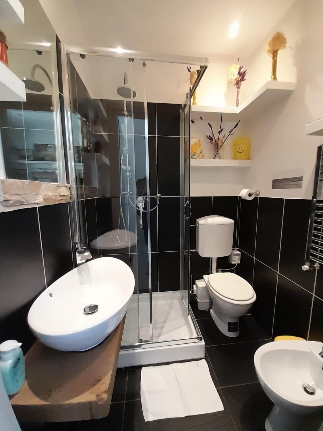 A modern bathroom with a glass-enclosed shower, a white sink, a toilet, and a bidet.
