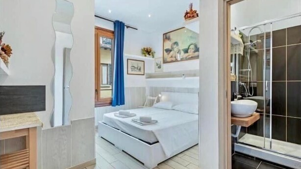A modern bedroom with a bed, bedside table, and a large window with curtains. - Guest house Biffi Simone (Florence)