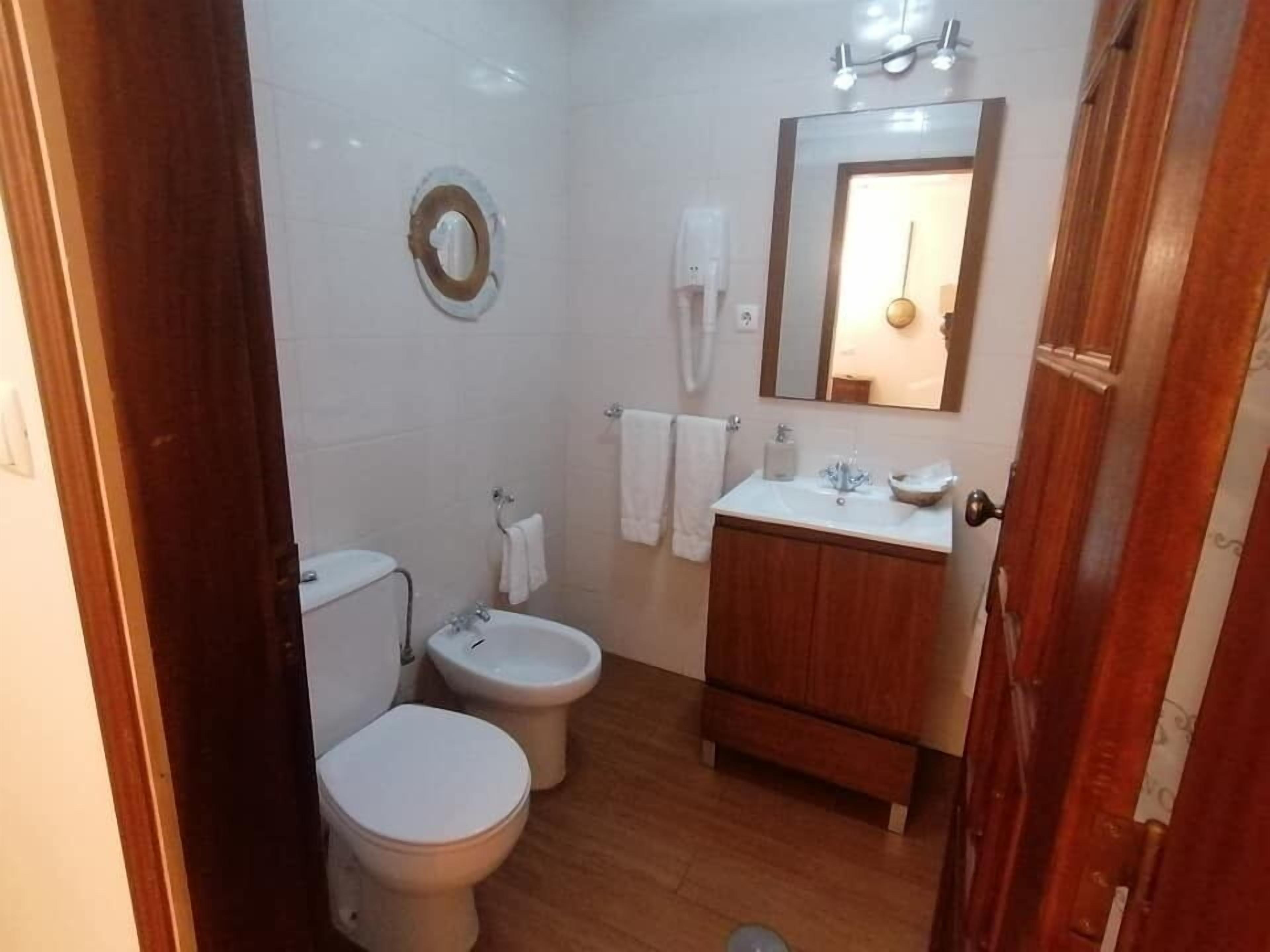 Un banyet petit amb vàter, bidet i lavabo amb mirall.