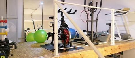 A home gym with exercise equipment, a wooden platform, and a mirror.