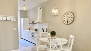 A modern kitchen with white cabinetry, a central island, and a dining area with white chairs and a round table. - ✪ Stylish apartment near the beach in the heart of Nice ✪ (Nice)
