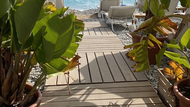 A wooden deck leading to a beach with blue and white striped umbrellas and lounge chairs. - ✪ Stylish apartment near the beach in the heart of Nice ✪ (Nice)