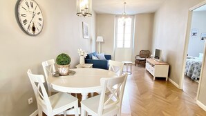 A dining area with a round table and chairs, a wall clock, and a chandelier. - ✪ Stylish apartment near the beach in the heart of Nice ✪ (Nice)