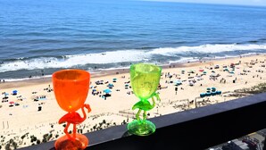 Vista para a praia com duas taças coloridas em um corrimão de varanda.