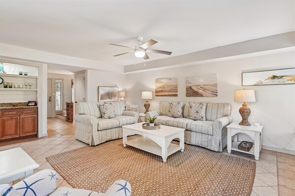 A spacious living room with a ceiling fan, two sofas with starfish cushions, a coffee table, and a rug. - Gorgeous Vacation Villa w/ Community Pool (Hilton Head Island)