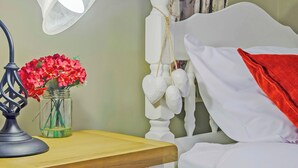 A neatly arranged bedroom with a wooden bedside table, a white bed with a red throw, a white lamp, and a vase of red flowers. - 2 bedroom accommodation in Caethro, near Caernarfon (Caethro, near Caernarfon)