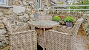 A stone building with a round table and wicker chairs. - 2 bedroom accommodation in Caethro, near Caernarfon (Caethro, near Caernarfon)