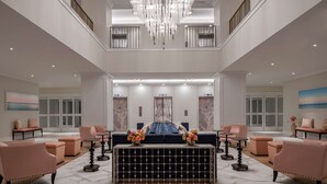 A spacious lobby with a central seating area, a chandelier, and a view of the upper floor. - Embassy Suites by Hilton Charleston Harbor Mt. Pleasant (Mount Pleasant)