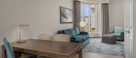 Une chambre d’hôtel moderne avec un coin repas, un canapé, une petite table et une vue sur la ville.