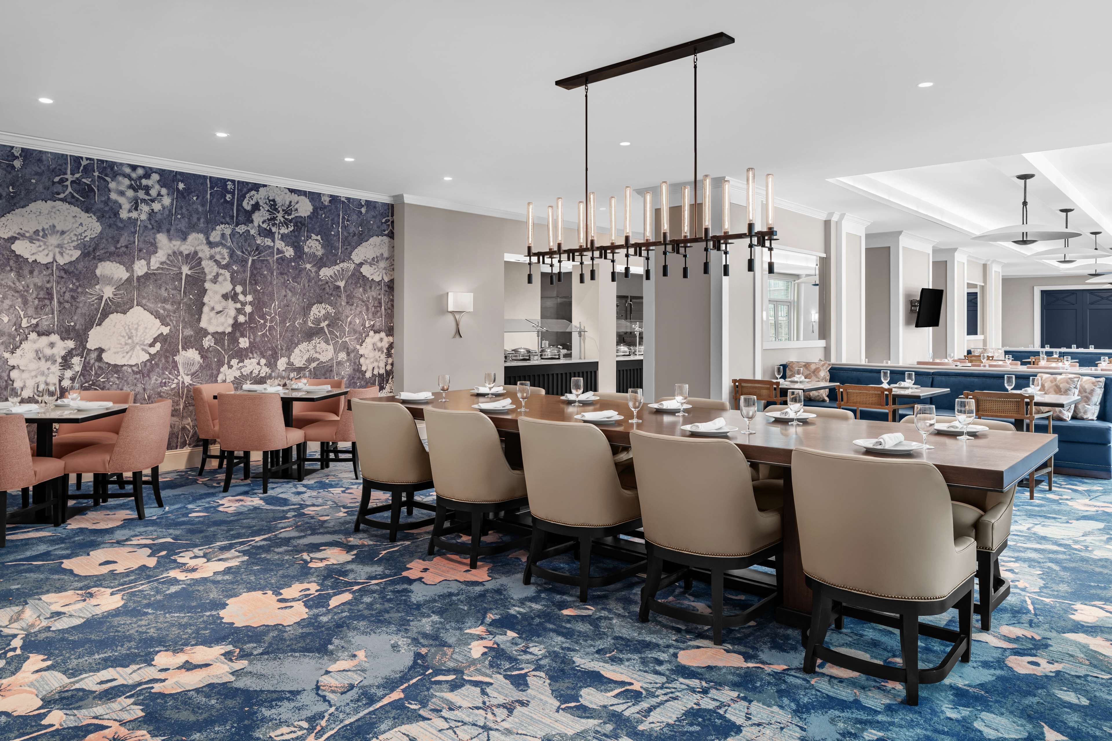 A modern dining area with a large table, multiple chairs, and a decorative wall.
