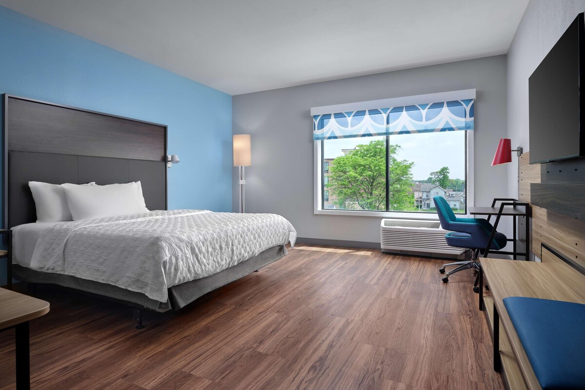 Een moderne hotelkamer met een bed, een bureau en een stoel.