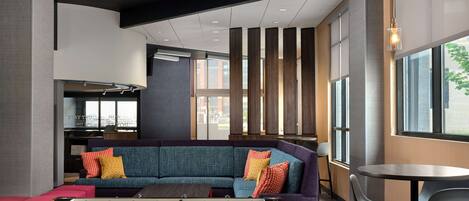 A modern lounge area with a sofa, foosball table, and a bar area with stools.