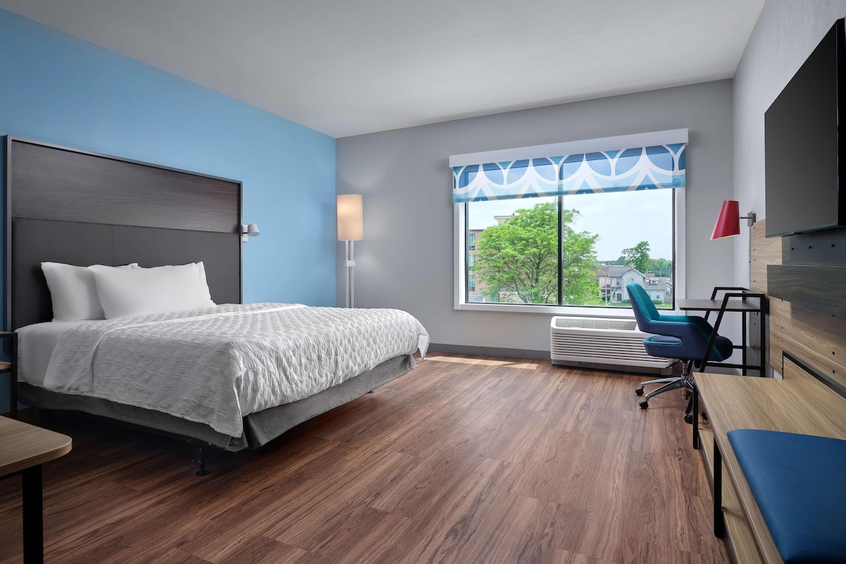 Une chambre d’hôtel moderne, équipée d’un lit, d’un bureau et d’une chaise.