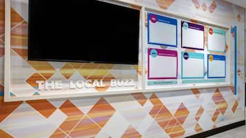 A bulletin board titled "THE LOCAL BUZZ" with various community boards and a large screen.