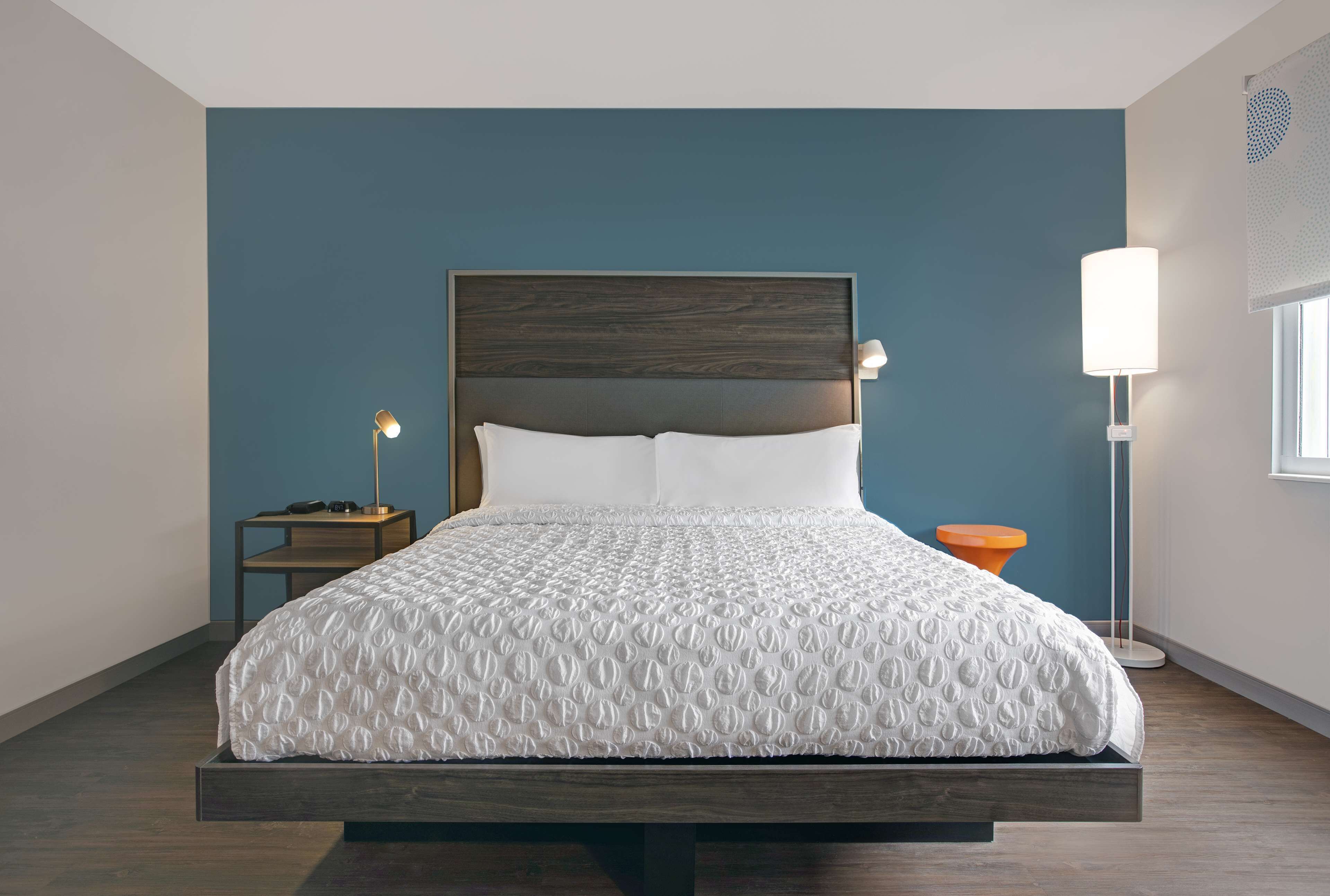 A modern bedroom with a bed, nightstands, and a floor lamp.