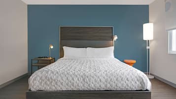 A modern bedroom with a bed, nightstands, and a floor lamp.