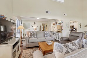 A living room with a sofa, a coffee table, a TV, and a dining area.