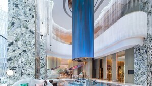 Un amplio vestíbulo con una piscina de cristal en el centro, paredes de mármol y un diseño de techo moderno.