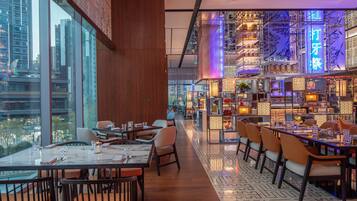 Um restaurante moderno com tetos altos, amplas janelas e vista para a paisagem urbana.