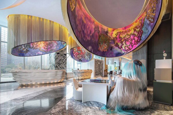 A modern interior with a reception desk, a large curved mirror, and a view of the cityscape through large windows.
