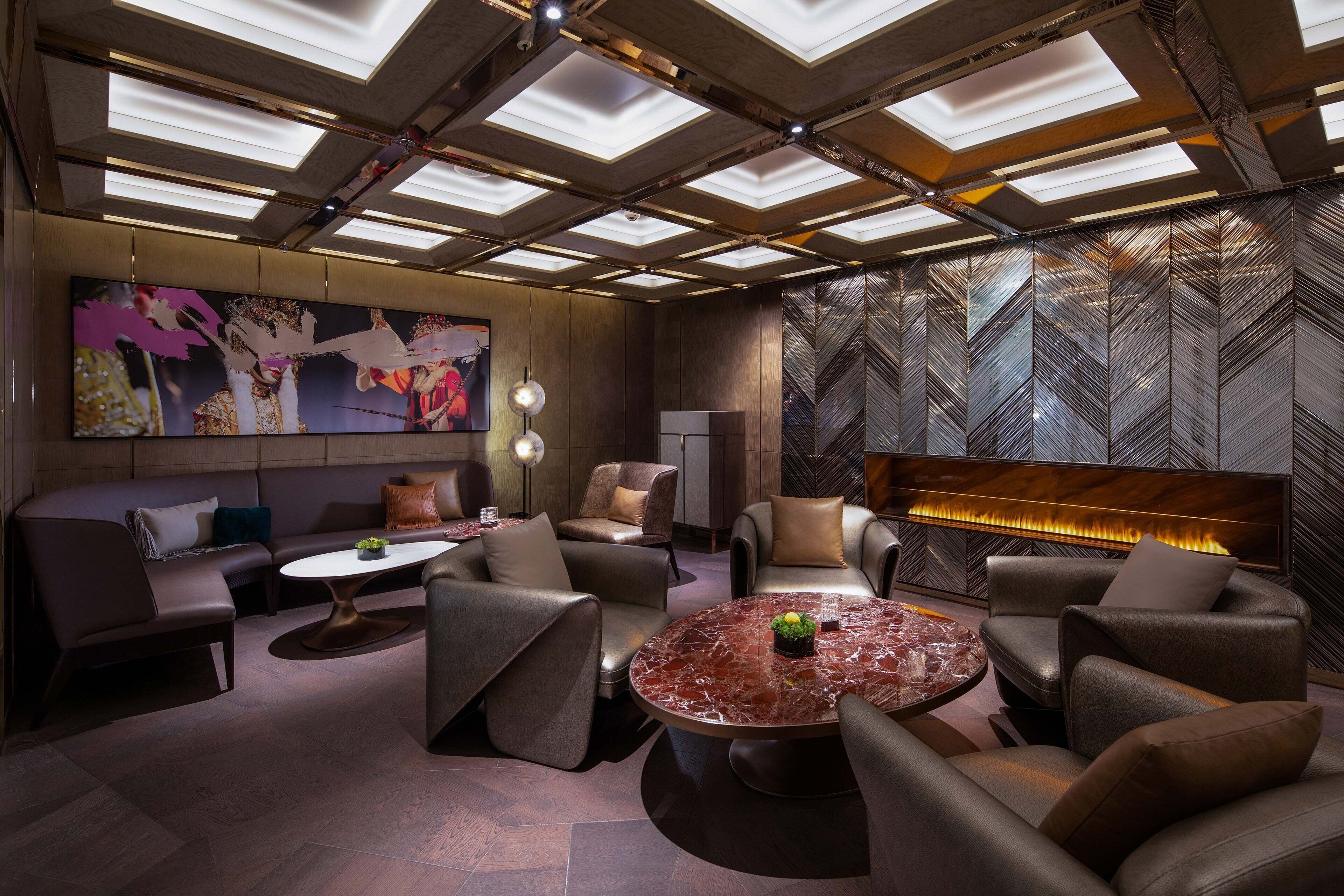 Un espace de détente moderne avec des canapés en cuir, une table basse en marbre et un grand tableau abstrait accroché au mur.