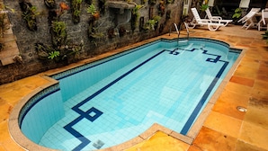 A rectangular swimming pool with a tiled edge, surrounded by stone tiles and potted plants. - Hotel São Paulo (Nova Friburgo)