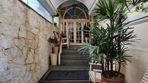 A stone-walled corridor with a wooden bench, a potted plant, and a door leading to a room. - Hotel São Paulo (Nova Friburgo)