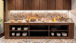 Eine moderne Küche mit Holzschränken, einer gemusterten Spritzschutzwand und einer Frühstückstheke mit verschiedenen Frühstücksartikeln und Besteck.