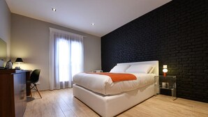 Ein modernes Schlafzimmer mit einem großen Bett, einem Schreibtisch mit Stuhl und einer Wand als Akzent in Ziegeloptik.
