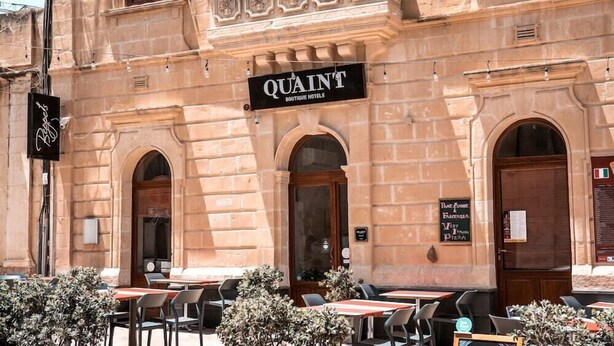 Ein charmantes Boutique-Hotel mit Außenbestuhlung und einem Schild, das auf ein Pizza-Restaurant in der Nähe hinweist.