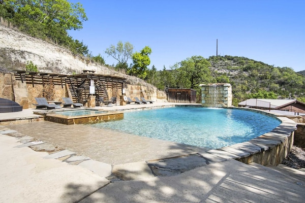 Relax by the infinity-edge pool with waterfall, lounge seating, and stunning hill country views.