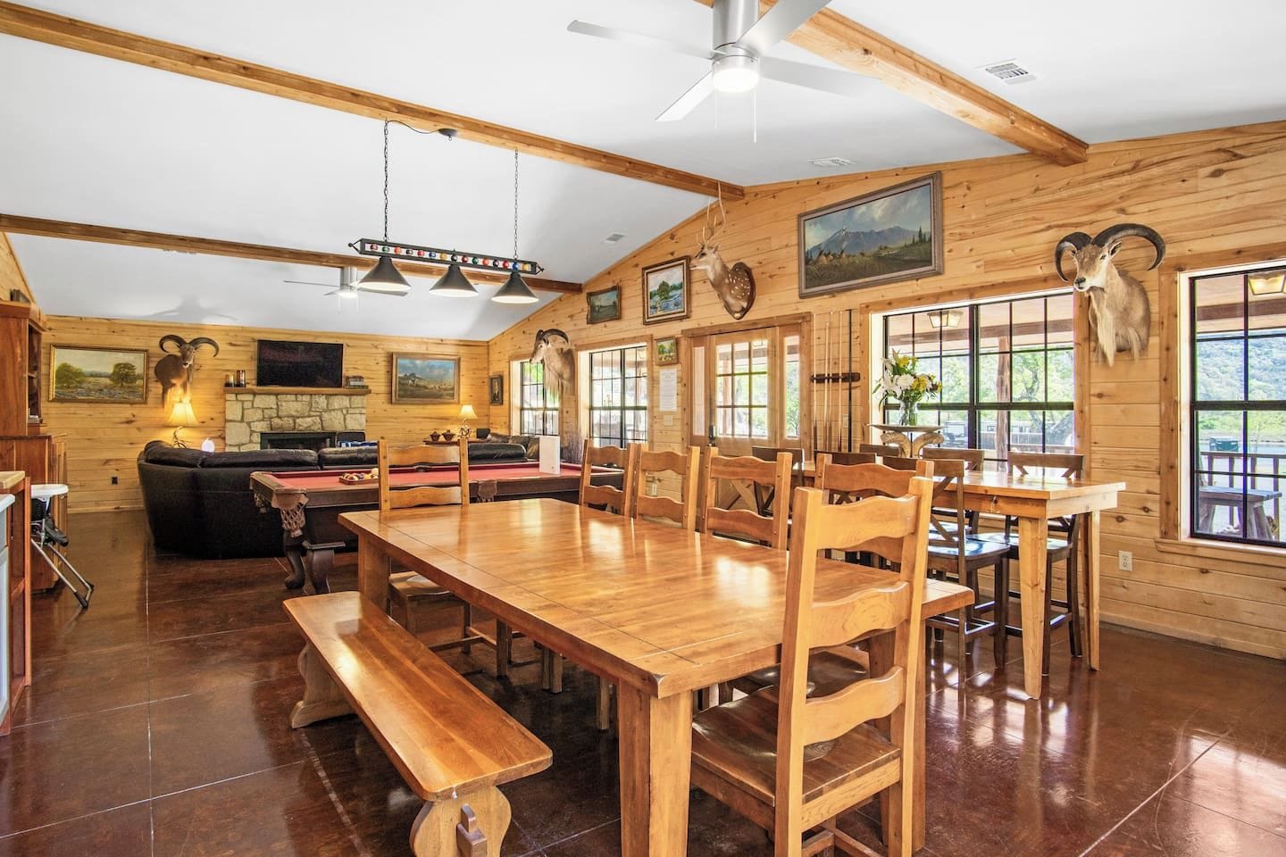 A wooden interior with a dining area, benches, and a fireplace.