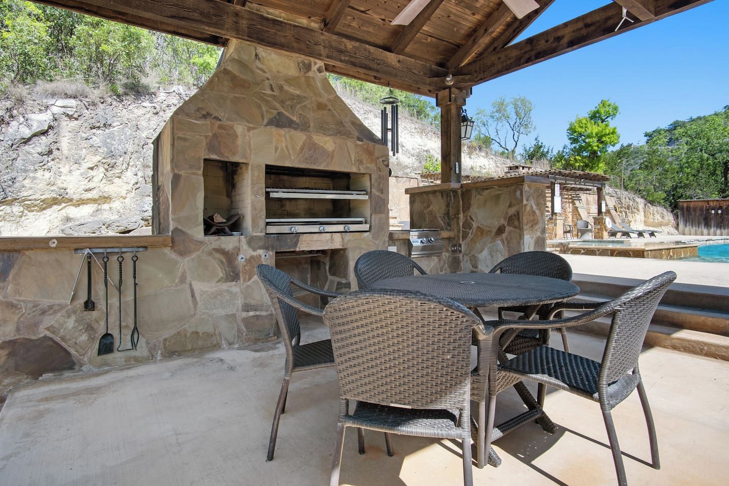 An outdoor patio with stone walls, a stone oven, and wicker furniture.
