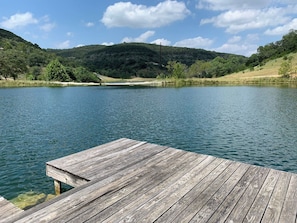 A wooden dock extending into a calm lake with a hilly landscape in the background.